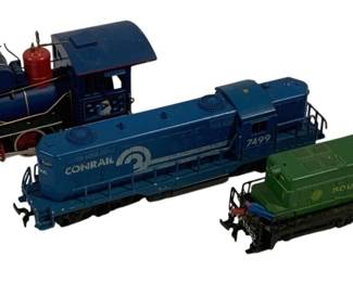 1574 - 3pc Lot Assorted HO Scale Locomotives (Description): A collection of three assorted HO scale  locomotives. The lot includes a vintage-style  steam locomotive with red accents and cow  catcher, a blue Conrail diesel locomotive  numbered 7499, and a green Southern railway diesel locomotive. All three are detailed  model trains suitable for HO scale layouts.