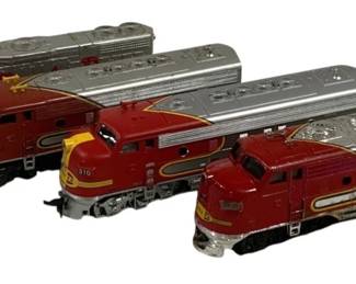 1573 - 4pc Lot Santa Fe Locomotives HO Scale (Description): A lot of four Santa Fe locomotive models in  HO scale. The collection features diesel  engines in the classic Santa Fe red and  silver 'Warbonnet' livery with yellow  accents. Includes engine number 3500 among the pieces. The locomotives display varying  degrees of wear consistent with vintage model  train collectibles.