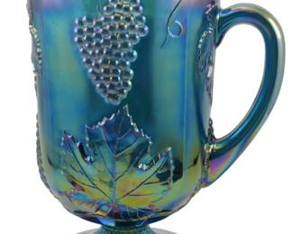 697 - Indiana Blue Harvest Grape Carnival Pitcher (Description): Vintage Indiana Electric Blue Harvest Grape  Carnival Glass Pitcher featuring an  iridescent finish with raised grape clusters  and grape leaf motifs. The footed pitcher  displays the characteristic rainbow iridescence of carnival glass with  predominantly blue, purple, and golden tones.  Measures 10.5" tall.
