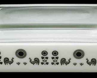 1223 - Pyrex Rooster Sunflower Covered Casserole (Description): Pyrex Rooster Sunflower covered casserole  dish featuring the classic mid-century  pattern with black roosters and stylized  sunflower motifs on white milk glass.  Includes clear glass lid. Measures 4 inches high by 11.5 inches long by 7 inches wide.