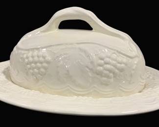 2003 - White Ceramic Covered Butter Dish 4.5"x9" (Description): White ceramic covered butter dish featuring  an embossed grape and vine motif. The domed  lid has a curved handle and sits atop a  matching plate with coordinating relief  decoration around the rim. Measures 4.5 inches by 9 inches.