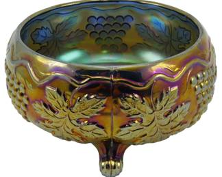731 - Northwood Grape & Cable Amethyst Glass Bowl (Description): Vintage Northwood Grape & Cable pattern bowl  in amethyst carnival glass. This footed bowl  features the classic grape cluster and cable  design with detailed grape leaves in relief  around the exterior. The iridescent finish displays brilliant gold, purple, and green  hues characteristic of fine carnival glass.  The bowl rests on decorative ball feet.  Measures 2 1/2 inches tall by 8 inches in  diameter.