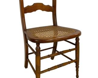 7672 - Victorian Walnut Chair w/ Cane Seat 33"x16"x17" (Description): Featuring a woven cane seat. The chair is  crafted from warm-toned wood with a honey  finish and displays two shaped horizontal  back slats. It stands on turned front legs  with ring details and slightly splayed rear legs, connected by stretchers for stability.  The chair measures 33 inches tall by 16  inches wide by 17 inches deep.