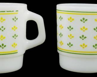 1114 - Pr Vtg Federal Leaf 2 Color Mugs 3.5" (Description): Pair of vintage Federal Glass leaf pattern  mugs measuring 3.5 inches. These milk glass  mugs feature a distinctive two-tone leaf  design in rows of two. One mug displays the  pattern in shades of blue, while the other showcases green and yellow leaves.Each leaf  motif includes a white feather or fern detail  within. Classic mid-century American  glassware with the characteristic D-handle  design.1113 - Pr Vtg Thermocrisa Green & Yellow Milk Glass (Description): Pair of vintage Thermocrisa milk glass mugs  featuring a charming green and yellow floral  motif. The white stackable mugs are decorated  with alternating green and yellow tulip-like  designs arranged in rows, bordered by coordinating green and yellow stripes at the  rim and base. These classic mid-century mugs  measure 3.5 inches tall.