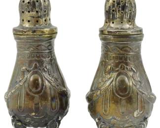 1010 - Pr Assumed Sterling Silver Footed Shakers (Description): Pair of unidentified shakers assumed to be  sterling silver. Each features an ornate  repousse design with swag and medallion  motifs, domed perforated tops with decorative  finials, and rests on four scrolled feet. The shakers display a patinated finish  consistent with age. Combined weight: 4.79  oz.