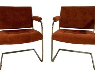 7597 - Pr Mid-Century Chrome Cantilever Armchairs (Description): A pair of mid-century modern cantilever  armchairs featuring chrome-plated tubular  steel frames with a sleigh base design. The  chairs are upholstered in rust-orange  suede-like fabric with tufted seats and padded armrests. The minimalist  Bauhaus-inspired design showcases clean lines  characteristic of 1970s modernist furniture.  Measures 30"x23"x26".