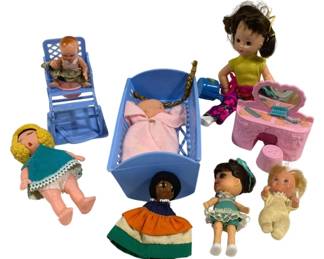 2015 - Assorted Baby Toys & Dolls Lot (Description): A charming lot of assorted baby toys and  dolls featuring various miniature figures and  accessories. The collection includes  multiple small dolls in different styles: a  baby doll in a blue plastic high chair, a swaddled baby in a blue rocking cradle with  braids, a blonde curly-haired doll in a teal  dress, a small celluloid-style baby doll, a  folk art doll in a colorful tiered skirt, a  dark-haired girl doll in a teal dress with