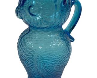 2009 - Blue Kanawha Glass Owl Figural Pitcher 5"x2" (Description): Blue glass pitcher in a figural owl design.  The textured molded glass features detailed  feather patterns throughout the body, with  the owl's face forming the spout area. The  piece has an applied handle on the side and rests on a footed base. Measures 5 inches by  2 inches.
