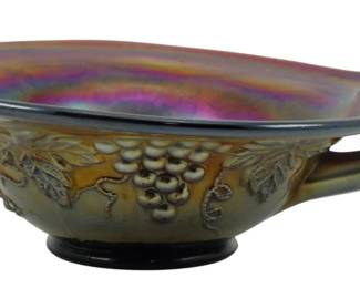 735 - Vtg Northwood Amethyst Grape & Cable Nappy (Description): Vintage Northwood Amethyst Grape & Cable  Carnival Glass Nappy. This beautiful piece  features the iconic Grape & Cable pattern  with raised grape clusters and vine leaves  encircling the exterior. The amethyst carnival glass displays a rich iridescent  finish with brilliant purple, gold, and  rainbow hues. The nappy has a gracefully  curved handle and sits on a pedestal foot.  Measures 2 1/2" x 5".