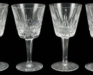 910 - 4 Waterford Crystal Lismore Wine Glasses (Description): A set of four Waterford Crystal claret wine  glasses in the classic Lismore pattern. Each  glass features the signature diamond and  wedge cut design characteristic of the  Lismore line, with a multi-sided stem and starburst cut base. The brilliant clear  crystal showcases the intricate cut pattern  that has made Lismore one of Waterford's most  beloved and recognizable designs.