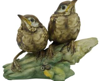 1075 - Turolia Merula Group Porcelain Bird Figure 6" (Description): Turolia Merula Group porcelain bird figure  featuring two fledgling thrushes perched on a  naturalistic branch with leaves and berries.  The birds are depicted with mouths open as  if calling, rendered in soft brown and tan tones with detailed feathering. The base  features green foliage and small dark  berries. Measures 6 inches.