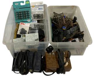 1588 - Lot Assorted Model Train Parts & Accessories (Description): Lot of assorted model train parts and  accessories including wheel sets, couplers  with instructions, transformers, track  pieces, and various structural components.  The collection features packaged items such as 33" flat back wheel sets and Walthers  railroad accessories, along with loose parts  stored in plastic bins. Transformers and  power supplies are included for layout  operation.