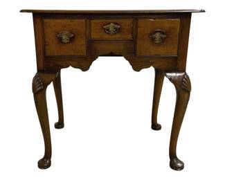 7753 - English Queen Anne Lowboy Table 20"x30"x20" (Description): Vintage Queen Anne style lowboy table crafted  in rich walnut with a warm patina. This  elegant piece features three drawers across  the front with decorative brass bail pulls  and an ornate escutcheon on the center drawer. The scalloped apron adds graceful  detail, while the cabriole legs are adorned  with carved shell motifs at the knees,  terminating in classic pad feet. The  rectangular top has a molded edge. Measures