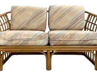 7735 - Bamboo Outdoor Love Seat -  32"x54"x32" (Description): Bamboo outdoor love seat featuring an open  lattice frame design with curved arms and  decorative bent bamboo detailing. The  two-seater includes four removable cushions  upholstered in a diagonal striped fabric in muted tones of peach, cream, gray, and blue.  The frame showcases wrapped rattan joints and  an airy, tropical aesthetic typical of  coastal or bohemian decor. Measures 32 inches  high by 54 inches wide by 32 inches deep.