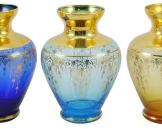 747 - 3 Vtg Venetian Art Glass Vases w/ Gold Trim (Description): Three vintage Venetian art glass vases  featuring elegant gold-toned rims, necks, and  decorative gilded scroll and floral motifs.  The set includes one cobalt blue, one light  blue, and one amber-yellow vase, each with a classic baluster form and gold-banded base.  Each vase measures 5 inches tall.