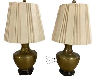 7633 - Pr of Brass Urn Form Table Lamps w/ Shades (Description): Pair of brass table lamps in a classic urn  form, each measuring 38 inches tall. The  lamps feature polished brass bodies with  elegant baluster shapes, mounted on carved  wooden bases with a dark finish. Each lamp is topped with a cream-colored pleated fabric  shade and brass ball finial. The  Asian-inspired design and substantial scale  make these lamps well-suited for traditional  or transitional interiors.