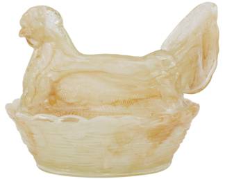 1046 - Pink Glass Hen on Nest Figure 5"x6"x4.5" (Description): Pink glass hen on nest figure featuring a  seated hen atop a woven basket-style base.  The piece displays a soft peachy-pink slag  glass coloration with subtle marbling  throughout. The covered dish design allows the hen lid to be removed from the nest base.  Measures 5" x 6" x 4.5".
