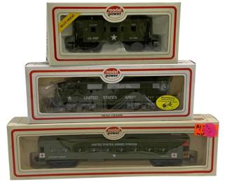 1600 - 3pc Model Power HO Scale US Army Train Cars (Description): A set of three Model Power HO scale United  States Army train cars in original packaging.  The collection includes a U.S. Army troop  carrier caboose, a United States Army  locomotive with metal chassis and magnetic knuckle couplers, and a United States Armed  Forces troop carrier/hospital car. All cars  feature military olive drab green paint  schemes with white star insignia and military  markings.
