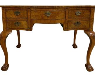 7738 - English Queen Anne Burl Desk 29"x39"x24" (Description): English Queen Anne style burl wood desk  featuring a serpentine front with five  drawers fitted with brass bail handles and  escutcheons. The desk rests on four elegant  cabriole legs with carved acanthus leaf decoration at the knees, terminating in bold  ball and claw feet. The richly figured burl  veneer top is crossbanded with a contrasting  border. Measures 29 inches high by 39 inches  wide by 24 inches deep.