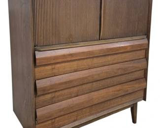 1417 - Lane First Edition Gentleman's Chest (Description): Lane gentleman's chest featuring fitted  drawers. This mid-century modern piece  showcases a walnut finish with distinctive  louvered drawer fronts and tambour door upper  cabinet. The chest rests on tapered legs characteristic of the period. Measures 48"  high x 40" wide x 18" deep.