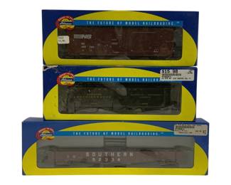 1616 - 3pc Lot Athearn HO Scale Train Cars (Description): A lot of three Athearn HO scale train cars in  original packaging. The collection includes  a Norfolk Southern boxcar numbered 450 769, a  Railway Express Agency express refrigerator  car numbered 3802, and a Southern gondola car numbered 52334. All cars are from Athearn's  'Ready to Roll' line, presented in their  signature blue and yellow display boxes  marked 'The Future of Model Railroading.'