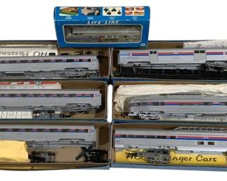 1662 - 5pc Lot HO Scale Train Cars in Boxes (Description): A lot of five HO scale train cars in their  original boxes. The collection includes  freight cars from various manufacturers  including Accuready and Accurail. Featured  railroads include Southern (car #66195) and Norfolk & Western. The cars include hoppers  and boxcars, all ready-to-run with  free-rolling metal wheels. Cars come in  original packaging with protective foam  inserts.1661 - 7pc Amtrak HO Train Set w/ Passenger Cars (Description): Seven-piece Amtrak HO scale train set  featuring multiple passenger cars and  locomotives in the classic Amtrak silver,  red, and blue livery. The set includes what  appears to be diesel locomotives and various passenger cars, presented in their original  boxes. Brands visible include Life-Like and  AHM HO Passenger Cars. A nice collection for  the HO scale model railroad enthusiast.