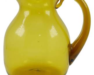 750 - Vintage Amber Glass Pitcher 7" (Description): Vintage amber glass pitcher featuring a  graceful bulbous body with a pinched spout  and applied amber handle. The hand-blown  glass exhibits a warm golden-yellow  coloration throughout. Measures 7 inches in height.