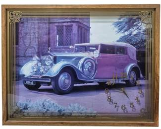 1429 - Wall Clock w/ Cars 21"x27" (Description): Wall clock featuring a classic car image. The  clock is set within a wooden frame with  decorative corner accents. Measures 21 inches  by 27 inches. Used as is  electric/electronic/mechanical item. No guarantee all components present, untested.
