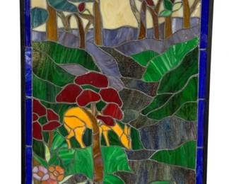 1505 - Stained Glass Window Deer Forest Scene (Description): Stained glass window panel depicting a scenic  forest landscape with a deer. The colorful  composition features a golden deer beneath  red-leafed trees, surrounded by lush green  foliage, a winding stream or path, and wildflowers in pink, orange, and blue in the  foreground. Trees with varied foliage frame  the background against a cream and golden  sky. The panel is bordered with cobalt blue  glass tiles and fitted with hanging loops at