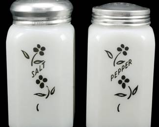 1021 - Pr McKee Climbing Vine Posey Shakers 5" (Description): Pair of McKee Climbing Vine Posey salt and  pepper shakers in milk glass with aluminum  screw-on lids. Each shaker features a black  floral vine design with the words "Salt" and  "Pepper" printed on the front. Measures 5 inches tall.