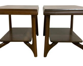 7601 - Pr Mersman Mid-Century Two-Tier End Tables (Description): A pair of mid-century modern nightstands or  end tables featuring a two-tier design with  sculptural curved legs. The tables are  crafted from walnut wood with a warm brown  finish. Each table has a square top with raised edges and a lower shelf, supported by  distinctive splayed legs with an elegant  curved stretcher base. Measures 20 inches  wide by 28 inches long by 20 inches high.
