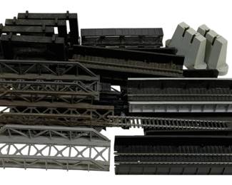 1673 - Lot HO Scale Train Track Accessories (Description): A lot of HO scale train track accessories  including various bridge sections, trestle  components, and track supports. The  collection features multiple truss-style  bridges, elevated track sections, and concrete-style pillars in black and gray  finishes, suitable for model railroad  layouts.
