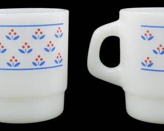 1100 - Set of 2 Vtg Thermocrisa Red & Blue Mugs (Description): Set of two vintage Thermocrisa milk glass  mugs featuring a charming folk-style floral  pattern in red and blue. Each mug displays a  decorative band with stylized three-petal  flowers bordered by blue horizontal stripes. The stackable design features the  characteristic D-shaped handle typical of  Fire-King style mugs. Measures 3.5 inches  tall.
