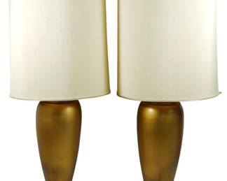 965 - Pr Mid-Century Gold Ceramic Table Lamps 35.5" (Description): Pair of mid-century modern table lamps  featuring elegant gold-tone ceramic vase-form  bodies with a brushed metallic finish. The  lamps rest on coordinating brass-toned metal  bases and are topped with original cream-colored drum shades with subtle  textured fabric. Each lamp measures 35.5  inches in height. Used as is electric/electronic/mechanical  item. No guarantee all components, untested.
