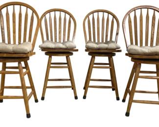 7644 - Set of 4 Oak Windsor Style Swivel Barstools (Description): Set of four oak Windsor style swivel  barstools featuring arched backs with spindle  detailing. Each stool has a round wooden  seat with removable tufted cushion in neutral  beige fabric. The four-legged bases include stretcher supports and protective rubber feet  caps. Measures 43 inches high by 20 inches  wide by 17 inches deep with a 24 inch seat  height.
