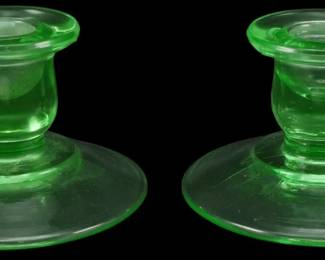885 - Pr Vtg Depression Uranium Glass Candlesticks (Description): Pair of vintage Depression era uranium glass  candlestands featuring a classic pedestal  design with wide circular bases and flared  candle cups. The translucent green glass  exhibits the characteristic glow associated with uranium glass from this period. Each  measures 3 inches.
