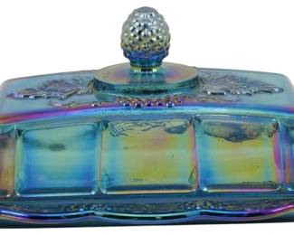 680 - Indiana Blue Harvest Grape Carnival Butter (Description): Vintage Indiana Electric Blue Harvest Grape  Carnival Glass Butter Dish. This covered  butter dish features the classic Harvest  Grape pattern with embossed grape clusters  and leaves decorating the lid and scalloped-edge base plate. The lid is topped  with a dimensional grape cluster finial. The  iridescent carnival glass finish displays  beautiful blue, purple, and golden rainbow  hues typical of this popular pattern.