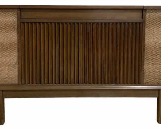 7620 - Mid-Century Motorola SK111W Stereo Console (Description): Motorola Mid Century record stereo console  model SK111W in working condition. This  vintage stereo features a walnut-toned wood  cabinet with classic mid-century modern  design, including a slatted front panel and woven speaker grilles on either side. The  console stands on tapered legs and has a  lift-top lid for turntable access. Used as is electric/electronic/mechanical  item. No guarantee all components, untested.