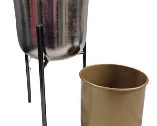 1439 - 2 Metal Planters, 1 on Stand 18"x9" (Description): Two metal planters, one featuring a polished  silver-tone finish set on a black metal  stand, and one gold-tone freestanding  planter. Measurements: 18 inches by 9 inches.
