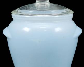 1219 - Small Blue Glassbake Jar w/ Lid 4.5"x3.5" (Description): Small blue Glassbake jar with clear glass  lid. The jar features a pale blue milk glass  body with a classic bean pot shape and small  tab handles on each side. The clear glass lid  has a round knob finial. Measures 4 1/2" x 3.5".
