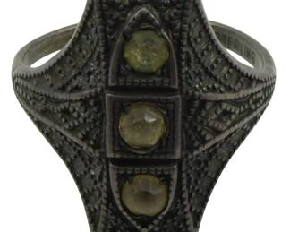 819 - Sterling Silver Ring with 3 Stones Size 7 (Description): Sterling silver ring in size 7 featuring an  ornate Art Deco style filigree design. The  elongated shield-shaped face is set with  three pale green-yellow stones arranged  vertically. The intricate metalwork displays detailed milgrain beading and geometric  patterns throughout. Weight: 0.13oz.
