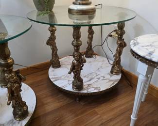 vintage Hollywood Regency style glass end table featuring ornate, gilded cherub or putti figures