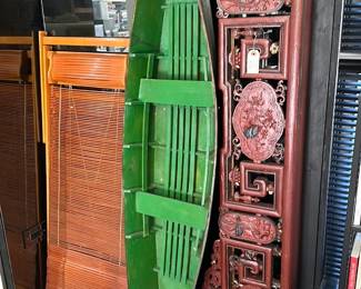 A vintage wooden canoe, its interior painted green; shown with a gorgeous large antique Chinese carved, red lacquered and gilt wood canopy from a wedding bed chamber, with detailed relief carved panels of central floral cartouche, flanked by two phoenixes and panels depicting flowers, auspicious objects such as Shou characters, a basket of peaches wishing longevity, cranes (known to mate for life) and pomegranates that connote blessings for many children and future generations. The two phoenixes together represent the male Feng and female Huang, symbolizing eternal love, peace, and harmony.