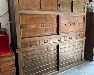 A beautiful antique two-section Japanese Mizuya Tansu, a kitchen or tea room chest, with hand forged iron hardware. In two sections, the upper portion has two sets of sliding doors with storage space behind each, and five side-by-side drawers along the lower part. The bottom section has 2 sliding doors with spacious storage with shelving behind. The top cabinet measures 74”W x 20-1/4”D x 39”H and the lower cabinet measures 74”W x 20-1/4”D x 28”H. Likely Meiji Period: (1880-1900). These chests are also known as daidokoro todana (kitchen shelves).