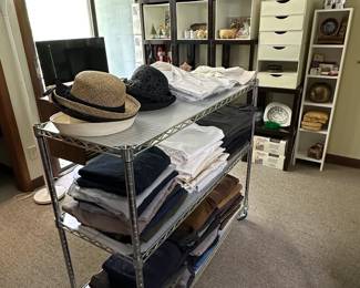 Women's vintage hats; vintage men's pants, trousers, jeans; bookshelves and storage cabinets, a rolling utility cart with adjustable chrome wire shelves and clear shelf liners