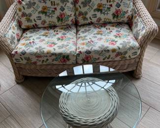 Upholstered wicker and rattan loveseat and rattan table with glass top