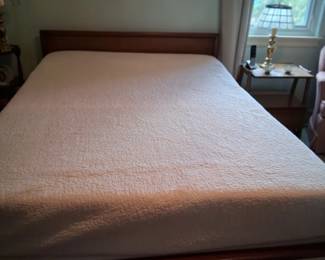 MCM bed frame with a woven square in the middle of the footboard.