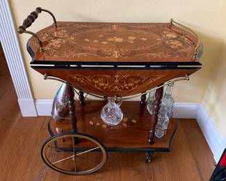 Mid-century Italian Sorrento marquetry bar cart or tea trolley. It features intricate floral fruitwood inlay, burlwood accents, drop-leaf sides, brass gallery rails, and a lower tier with bottle holders.