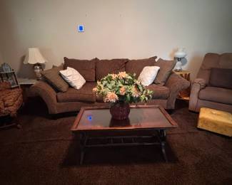 Brown Sofa and Wood Coffee Table  Large brown upholstered sofa with rolled arms and coordinating back cushions, paired with a rectangular wood-and-glass coffee table. Both pieces work well in a living room, family room, or den.