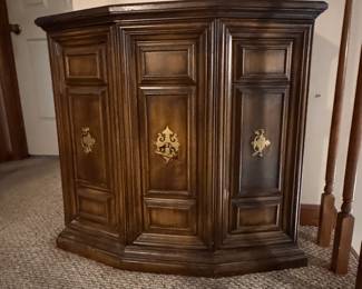 Ornate Dark Wood Accent Cabinet  Elegant dark wood cabinet featuring decorative raised-panel doors, a curved front, and antique-style brass hardware. This substantial piece offers hidden storage and would work beautifully in an entryway, dining room, living room, or hallway.